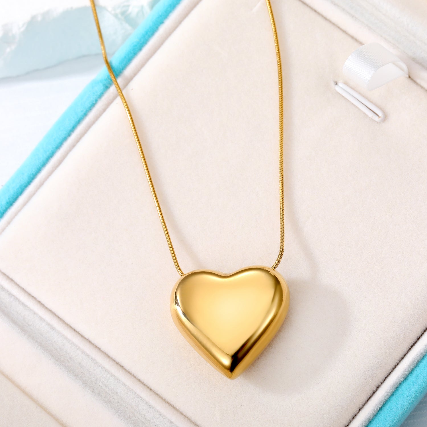 Elegant close-up of Golden Heart Necklace displayed on a velvet stand