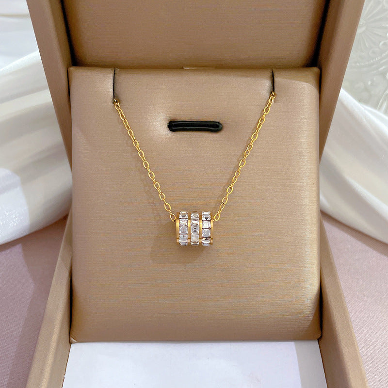 Elegant close-up of Golden Trinity Spark Necklace displayed on a velvet stand