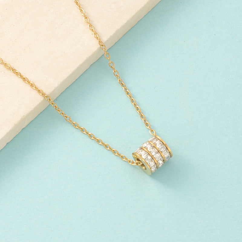 Elegant close-up of Golden Trinity Spark Necklace displayed on a velvet stand