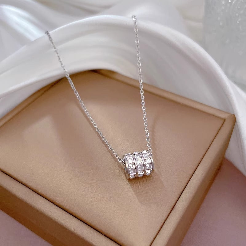 Elegant close-up of Silver Trinity Spark Necklace displayed on a velvet stand